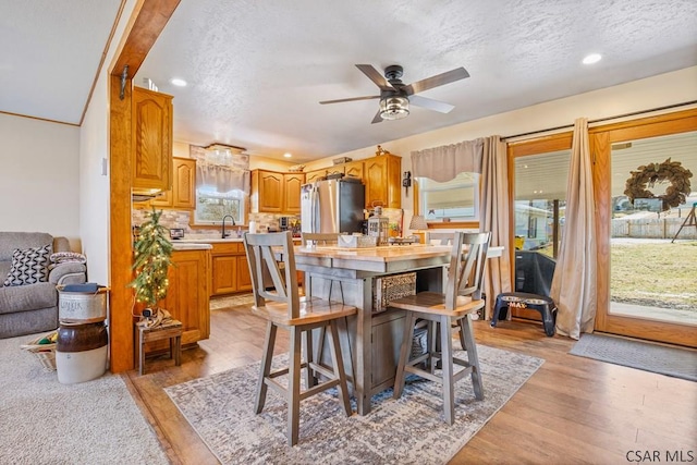 dining room featuring light wood-style flooring, a textured ceiling, a ceiling fan, and recessed lighting