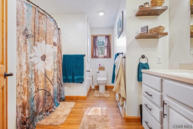 bathroom featuring toilet, vanity, wood finished floors, a shower with curtain, and baseboards