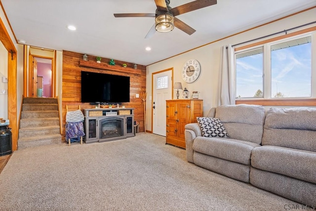 living room with a wealth of natural light, stairs, carpet flooring, and a glass covered fireplace