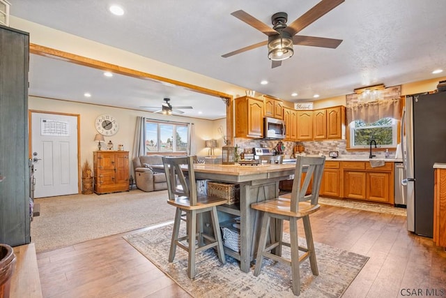 kitchen with light wood-type flooring, tasteful backsplash, appliances with stainless steel finishes, and light countertops