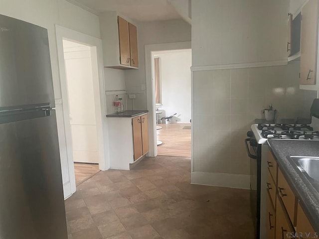209 Dupont St, Johnstown, PA 15902 - kitchen with freestanding refrigerator, gas stove, dark countertops, and brown cabinetry