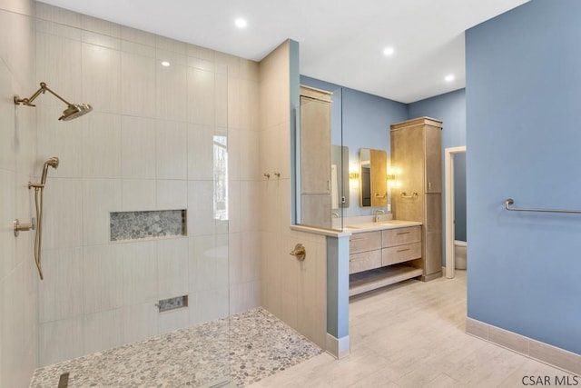 bathroom featuring tiled shower, vanity, and toilet