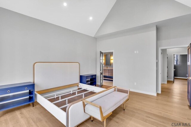 bedroom featuring ensuite bath, high vaulted ceiling, and light hardwood / wood-style floors