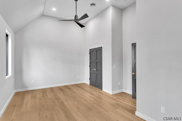 empty room with high vaulted ceiling, ceiling fan, and light wood-type flooring