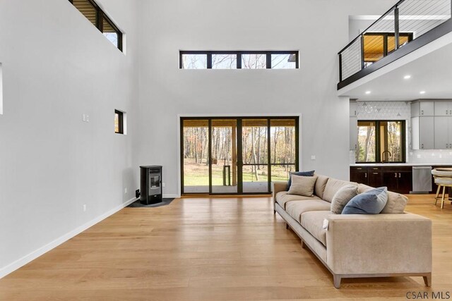 living room with sink, light hardwood / wood-style flooring, and a high ceiling