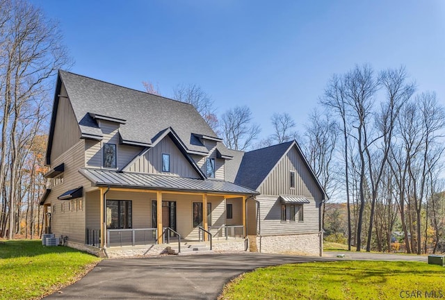 modern farmhouse style home featuring central AC unit, covered porch, and a front lawn