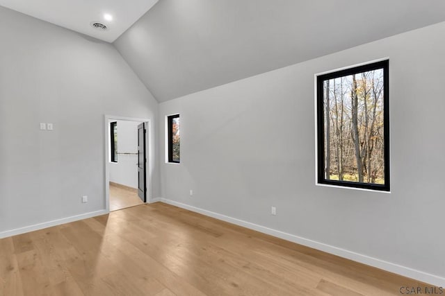 unfurnished room with vaulted ceiling and light wood-type flooring