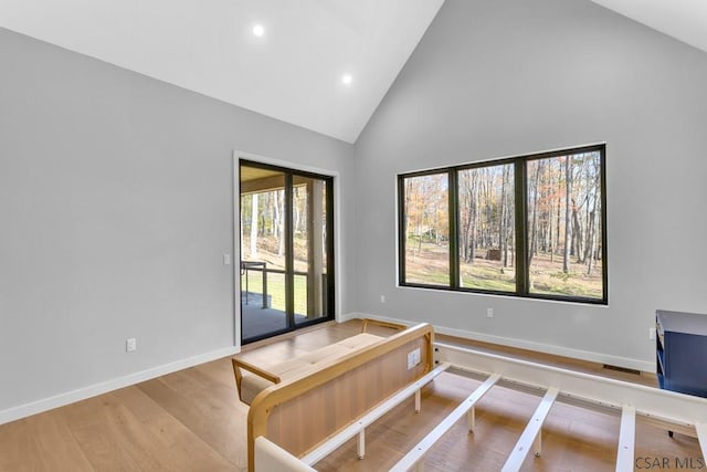 bedroom featuring hardwood / wood-style flooring, access to exterior, and high vaulted ceiling