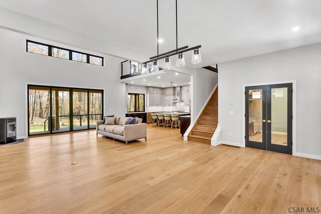 living room featuring a towering ceiling, light hardwood / wood-style floors, and french doors