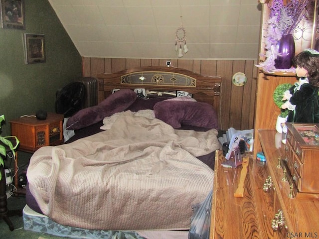 bedroom featuring wooden walls and vaulted ceiling