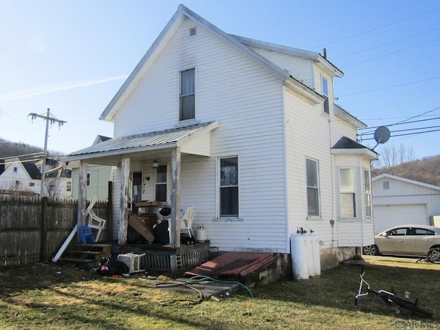 back of house featuring a yard, metal roof, and fence