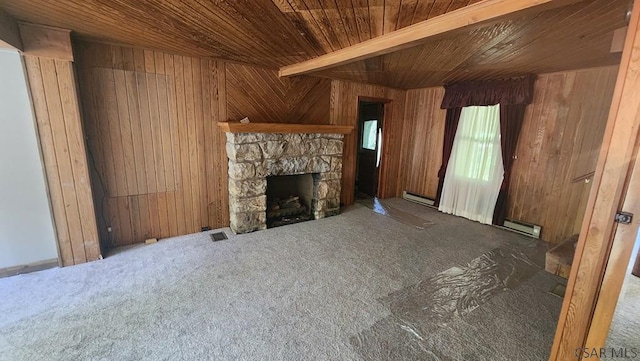 unfurnished living room with carpet flooring, a stone fireplace, a baseboard radiator, and wood walls