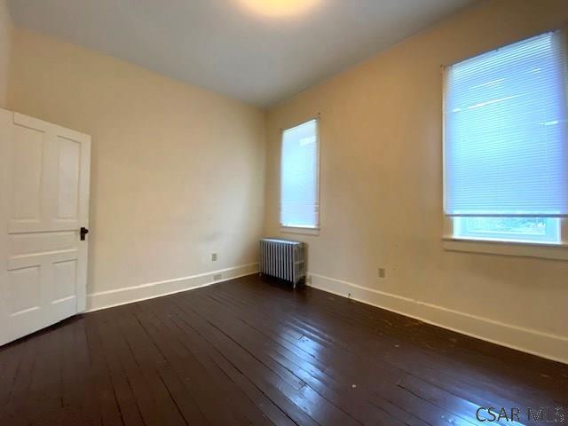 empty room featuring dark hardwood / wood-style floors and radiator