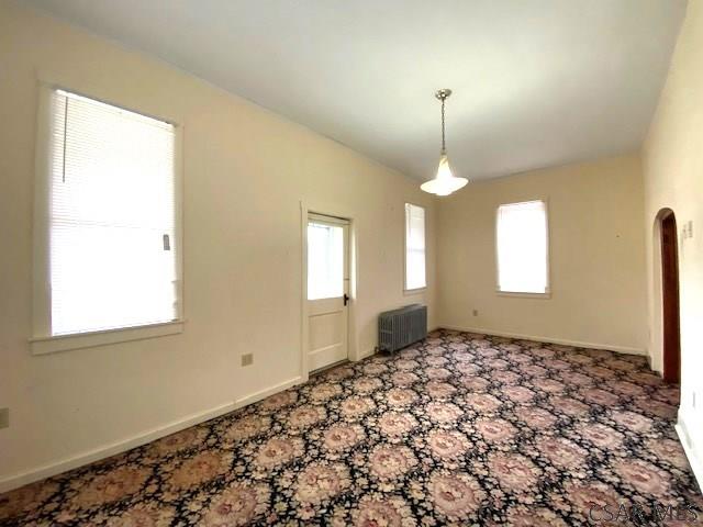 unfurnished room with radiator heating unit and carpet