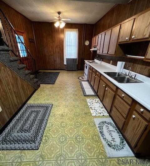 kitchen with white electric range, sink, radiator heating unit, wooden walls, and ceiling fan