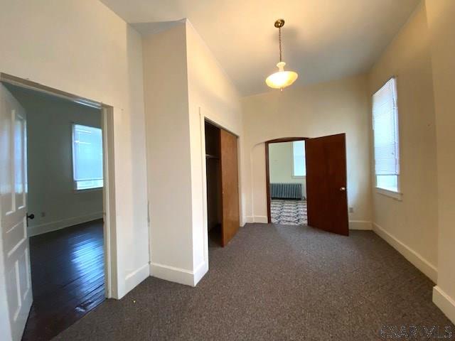 corridor with radiator heating unit and dark carpet