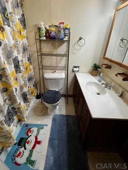 bathroom featuring tile patterned flooring, vanity, a shower with shower curtain, and toilet