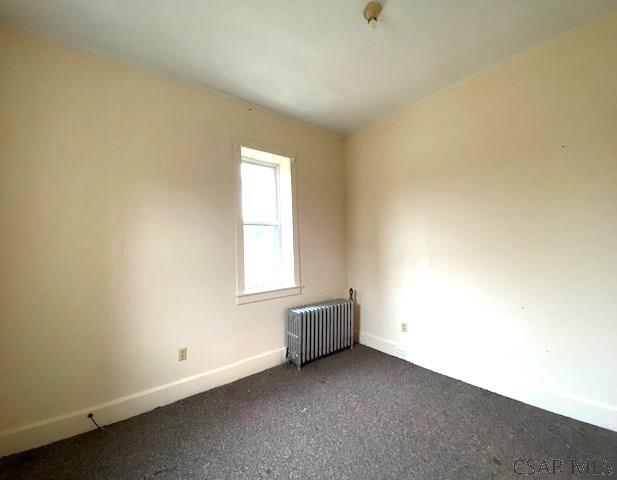 carpeted empty room featuring radiator