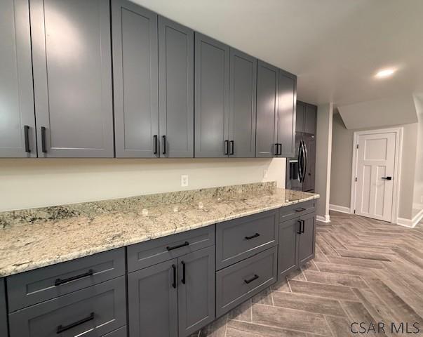 2200 Dundee Ln, Johnstown, PA 15905 - kitchen with gray cabinetry, light stone counters, refrigerator with ice dispenser, and baseboards