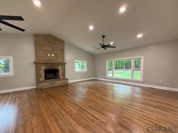2200 Dundee Ln, Johnstown, PA 15905 - unfurnished living room with ceiling fan, wood finished floors, vaulted ceiling, a stone fireplace, and baseboards