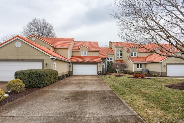 view of front of property featuring a garage, a tile roof, concrete driveway, stucco siding, and a front yard