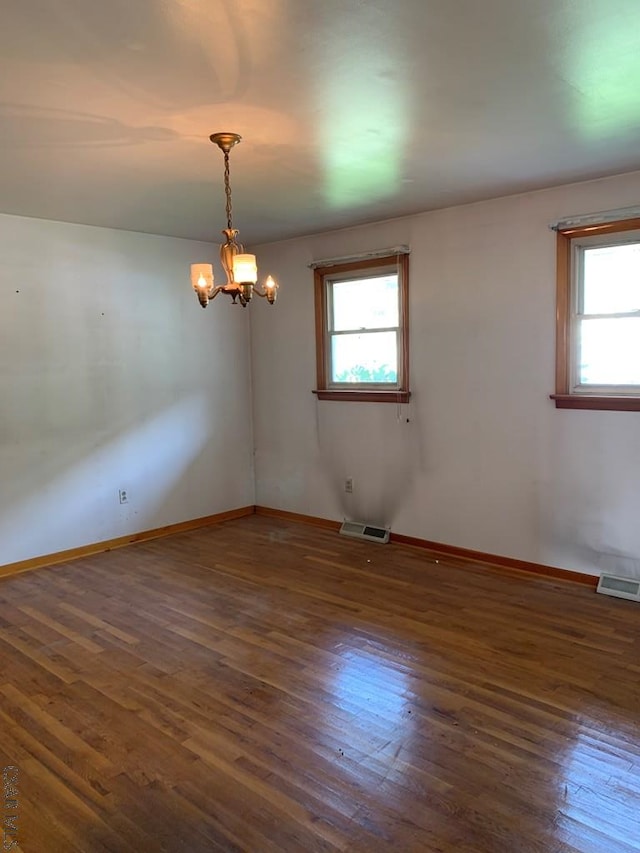 empty room featuring dark hardwood / wood-style flooring and a notable chandelier