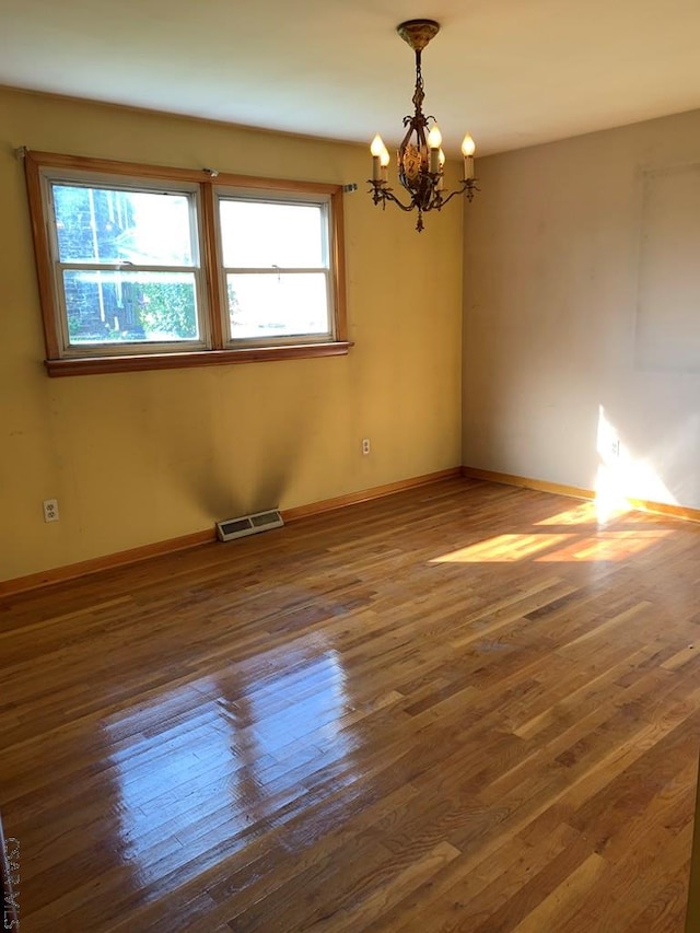 unfurnished room featuring dark hardwood / wood-style flooring and a chandelier