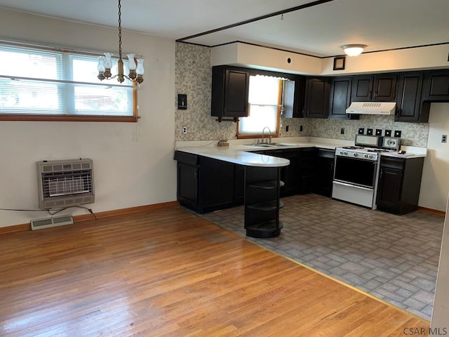 kitchen with pendant lighting, sink, heating unit, tasteful backsplash, and white gas stove