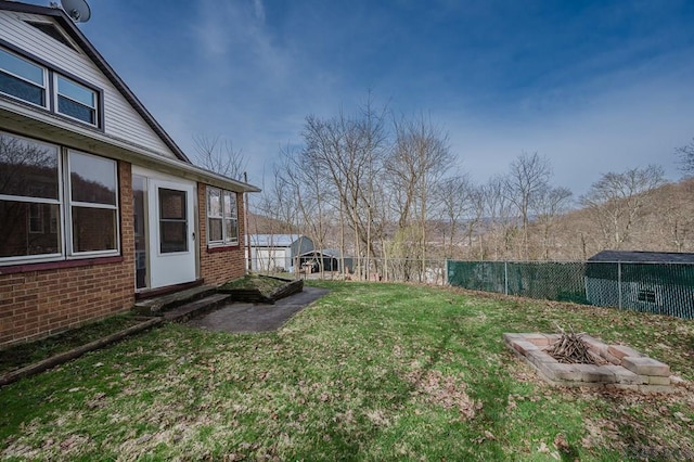 view of yard with an outdoor structure, an outdoor fire pit, fence, and entry steps
