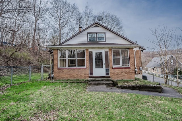 bungalow-style home featuring a front lawn, a gate, brick siding, and fence private yard
