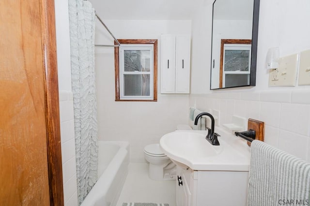 bathroom featuring toilet, vanity, tile walls, and shower / bath combo