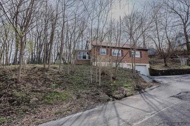 view of front facade with fence, driveway, an attached garage, and brick siding