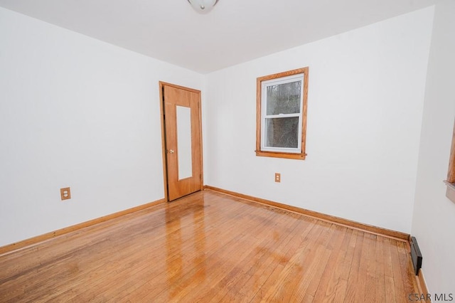 spare room with baseboards, a baseboard radiator, and light wood finished floors