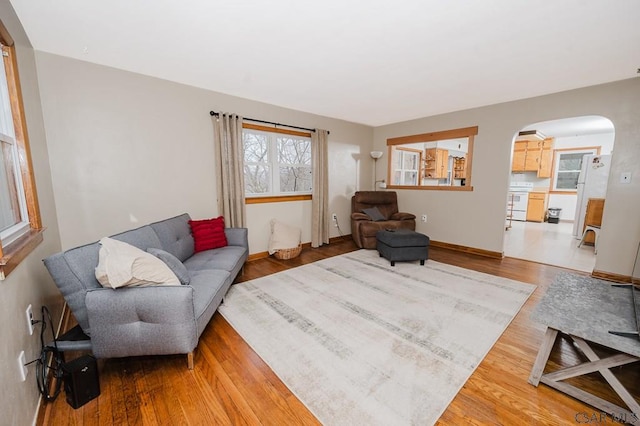 living area with arched walkways and wood finished floors