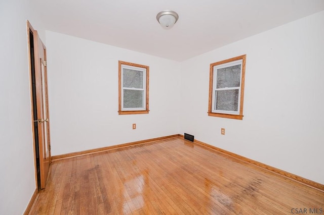 spare room featuring baseboards and light wood finished floors