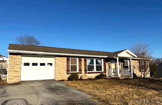 single story home with a garage, brick siding, covered porch, and aphalt driveway