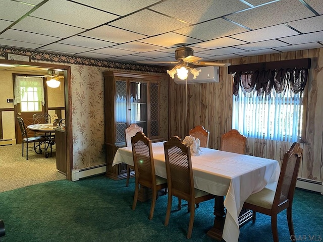 carpeted dining room with wooden walls, ceiling fan, and baseboard heating