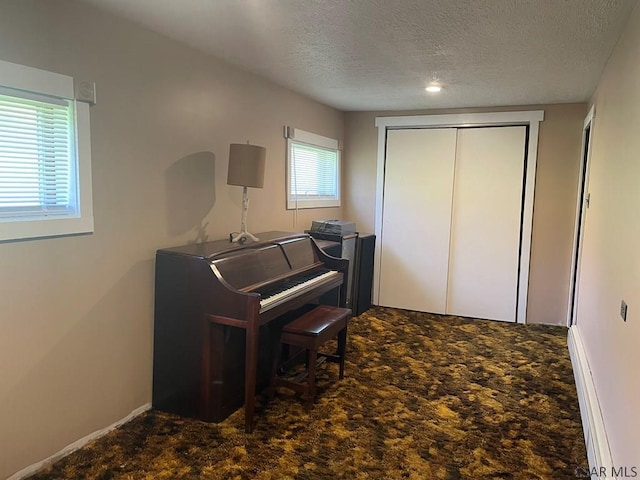 carpeted office with baseboards and a textured ceiling