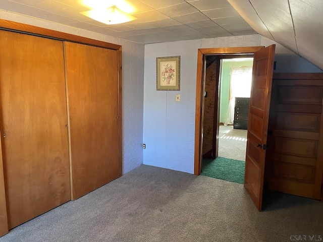unfurnished bedroom featuring carpet, vaulted ceiling, and a closet