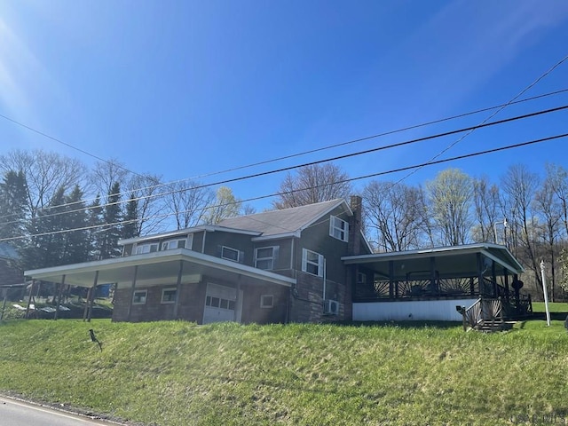 view of side of home featuring a chimney, a carport, and a lawn