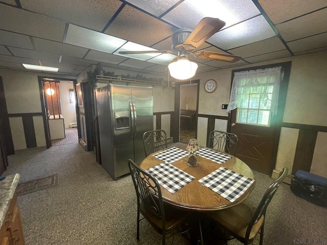 carpeted dining area with a ceiling fan and a paneled ceiling