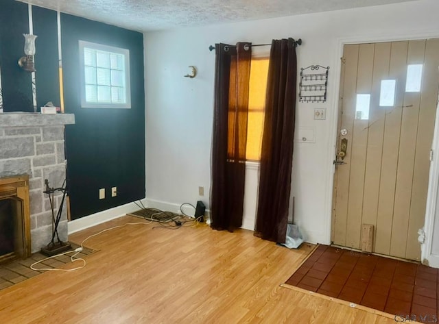 entrance foyer featuring wood-type flooring, a textured ceiling, and a fireplace