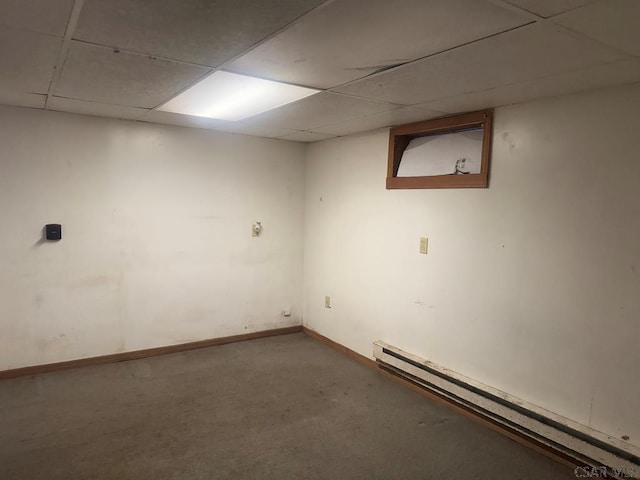 basement featuring a paneled ceiling, carpet flooring, and a baseboard heating unit