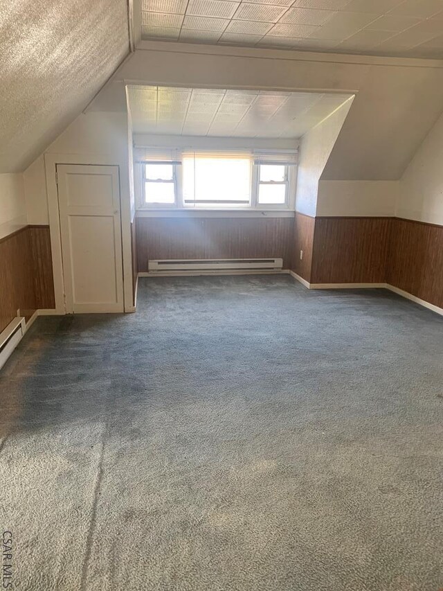 additional living space with lofted ceiling, dark carpet, and baseboard heating