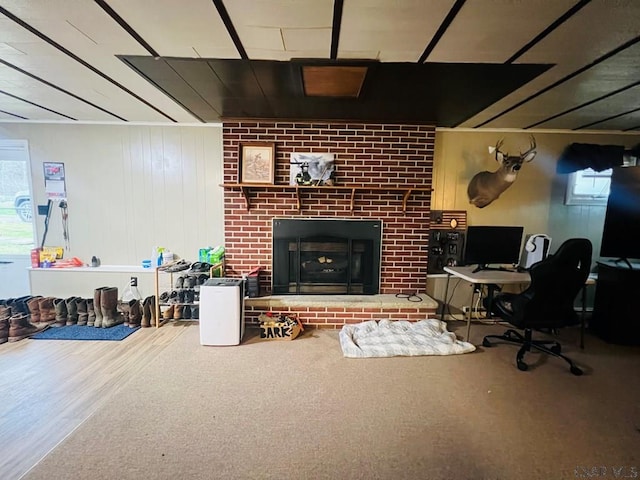 home office with a brick fireplace and wood walls