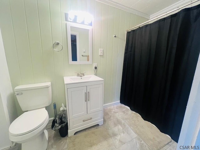 bathroom featuring vanity, wooden walls, ornamental molding, and toilet