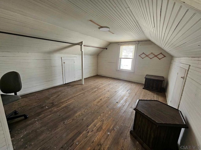 additional living space with vaulted ceiling, hardwood / wood-style floors, and wooden walls