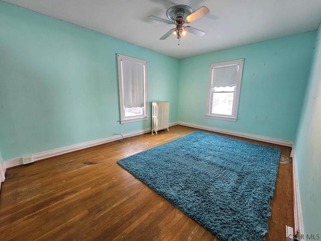 spare room with ceiling fan, radiator heating unit, and wood-type flooring