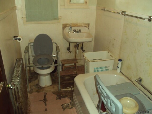 bathroom featuring radiator heating unit, toilet, sink, and a washtub