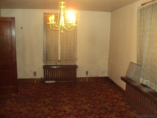 spare room featuring an inviting chandelier and radiator